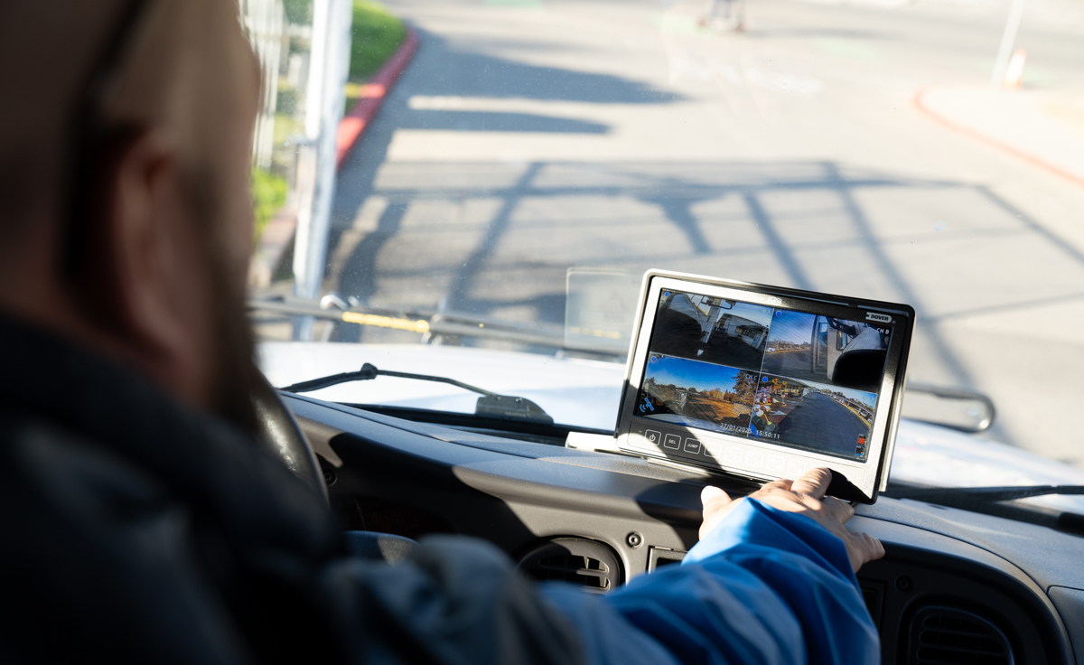 driver looks at 360 camera screens inside bus
