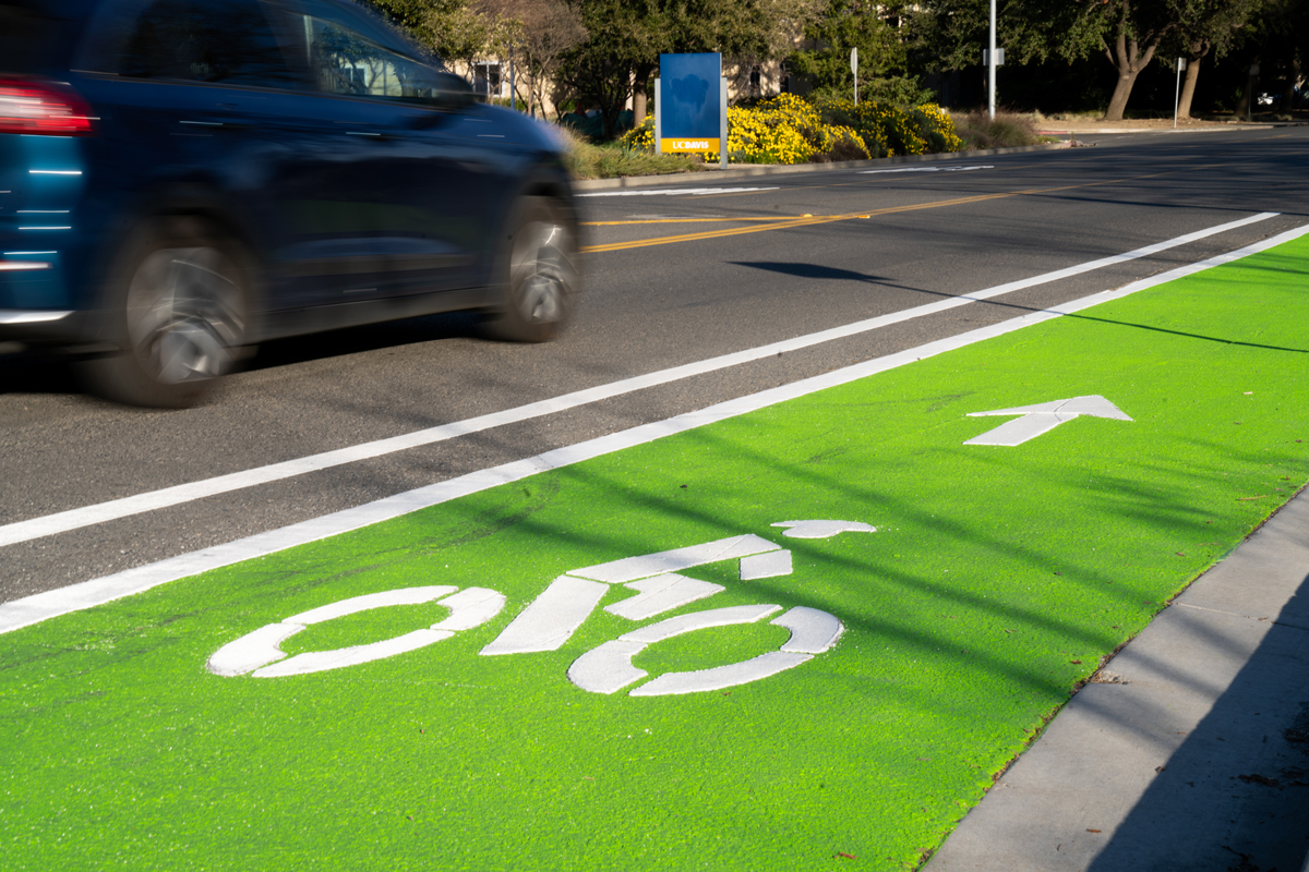car zooms next to a bright green bike lane