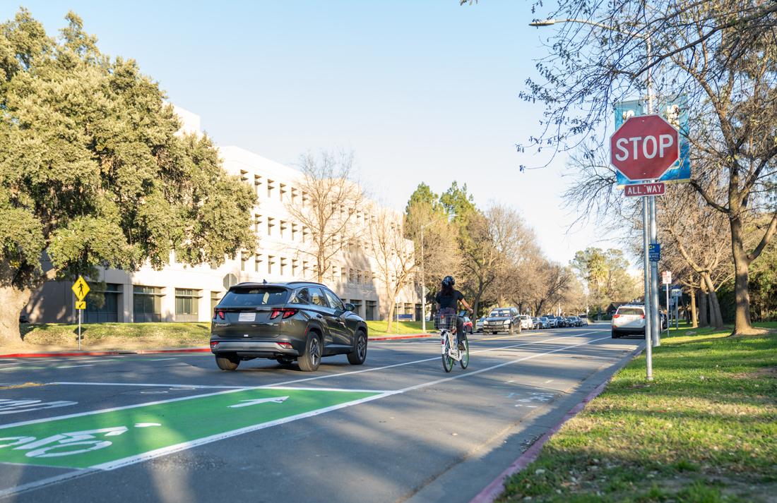 car and bicycle on UC Davis campus on La Rue Road near Bioletti Way, with new stop sign and fresh bike lane paint
