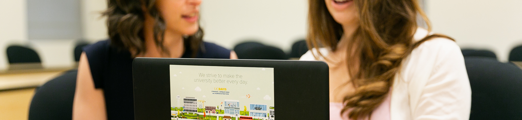two female employees talking with one another while looking at a laptop